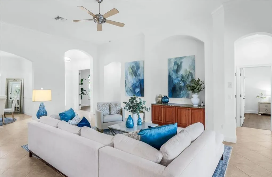 After: “Living room staged with coastal furnishings, natural textures, and soft blue accents by Naples Home Staging” Before: “Vacant living room before staging with blank walls and no defined layout” Detail: “Staged living room seating area with woven textures, modern sofa, and coastal artwork”
