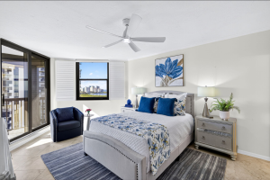 Staged bedroom in a Pelican Bay high-rise with ocean views and coastal décor